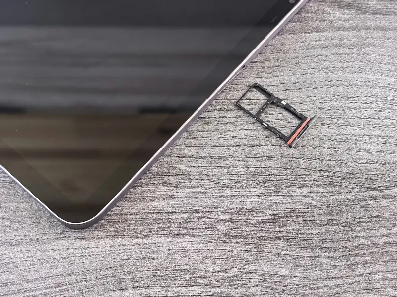 Smartphone on a wooden desk with its SIM card tray removed beside it