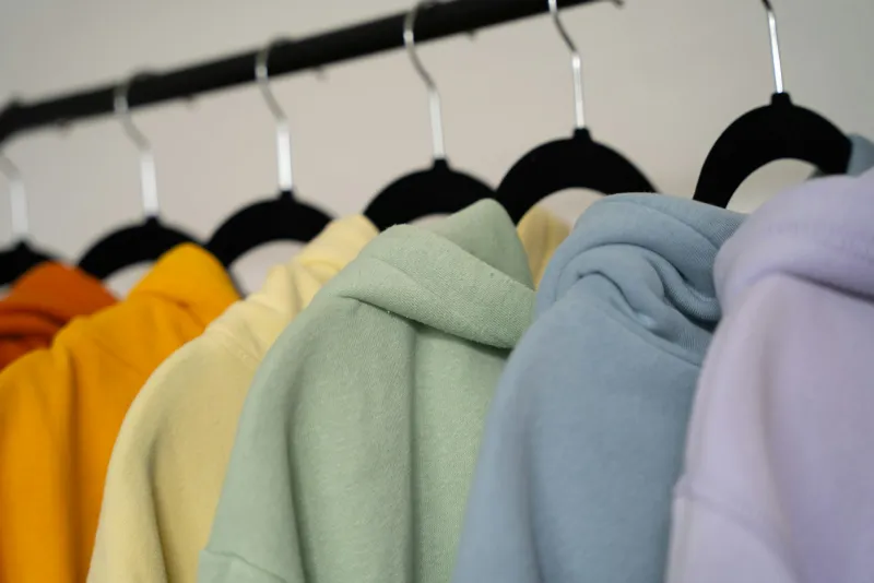 Pastel-coloured hoodies hanging in a row on a clothes rail
