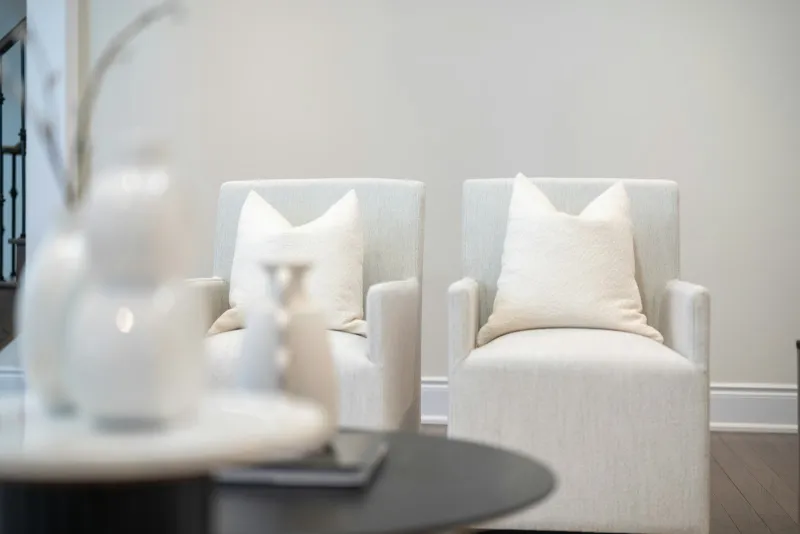 Two white armchairs with cushions in a calm, softly lit room