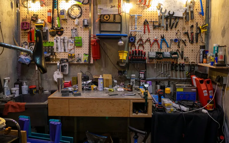 A bike workshop bench with spanners, pliers and spare parts hanging on pegboards