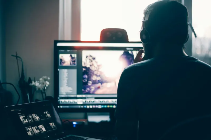 Retouch4me: AI retouching plugins that take the routine out of photo editing Person in headphones editing a photo on a large monitor beside a laptop