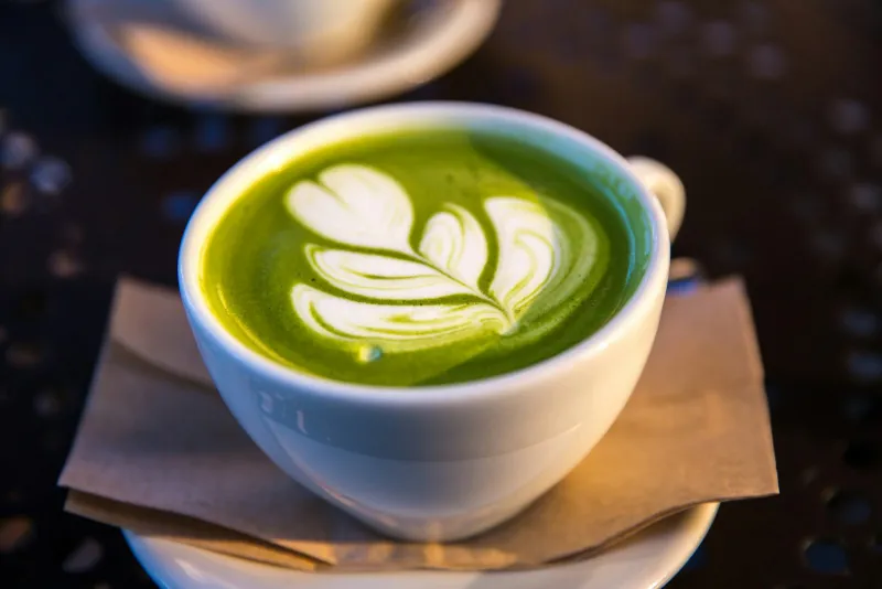 A white cup of frothy green matcha tea