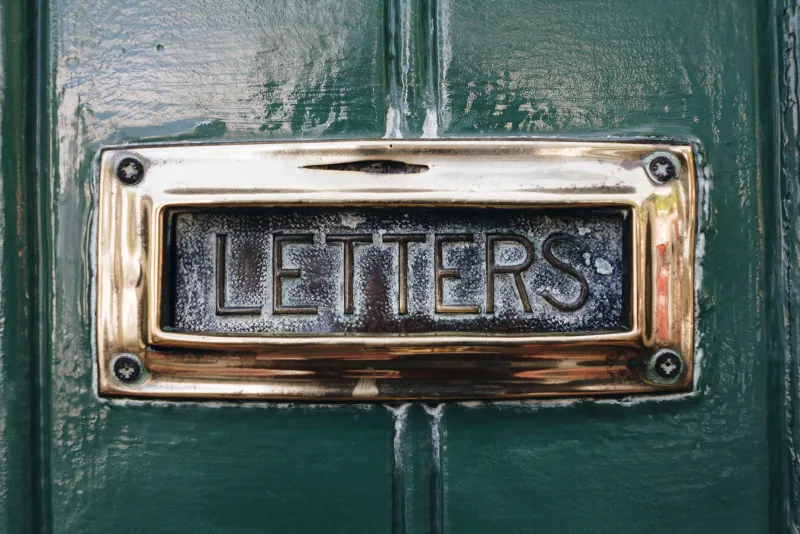 Brass letterbox marked Letters on a green front door