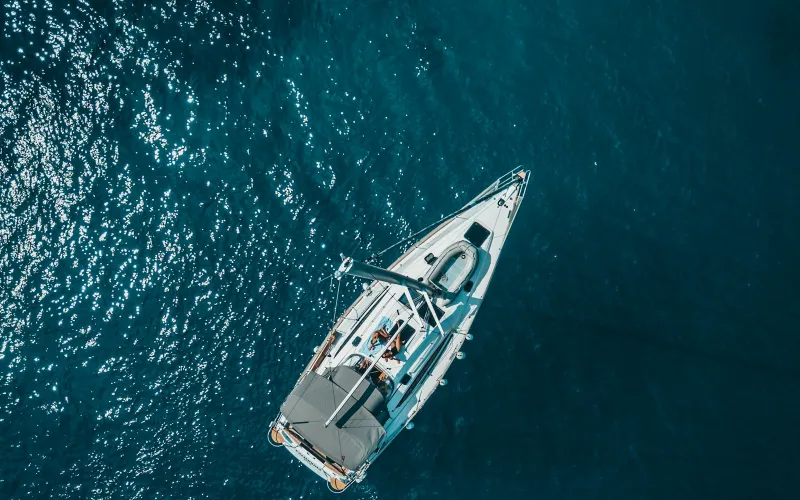 SamBoat: hire a boat for the day or the week, with or without a skipper Aerial view of a white sailing yacht on deep blue Mediterranean water off Hvar