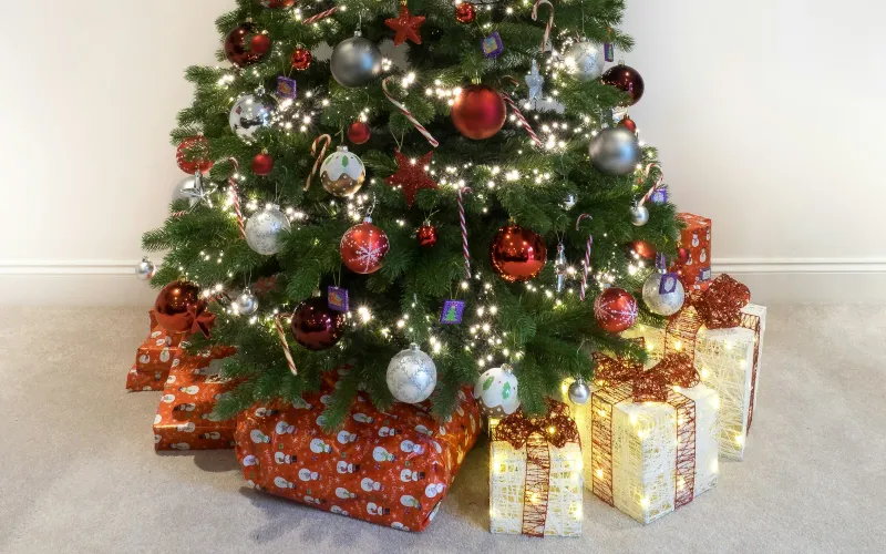 A decorated Christmas tree with wrapped presents and light-up gift boxes underneath