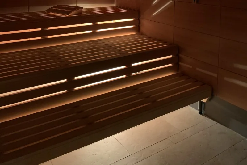 Wooden sauna benches lit from below with warm light