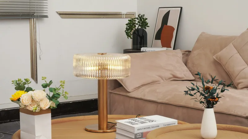 A ribbed glass table lamp on a wooden coffee table in a living room