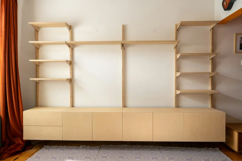 A light wood wall unit with open shelves above a long run of low cabinets
