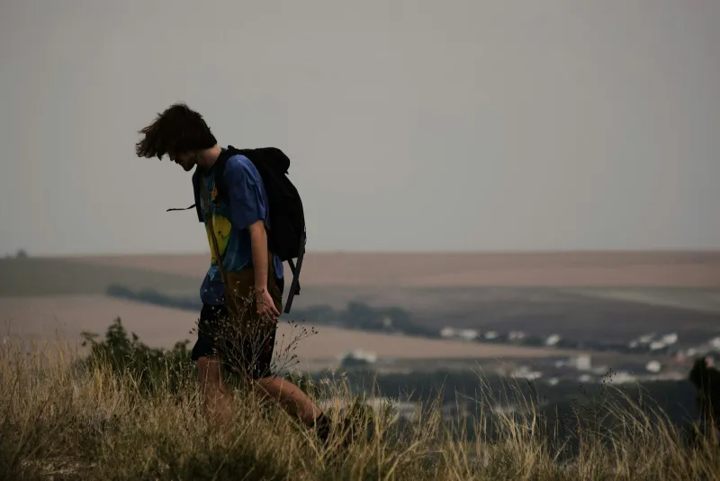 Walker with a rucksack crossing a grassy hillside