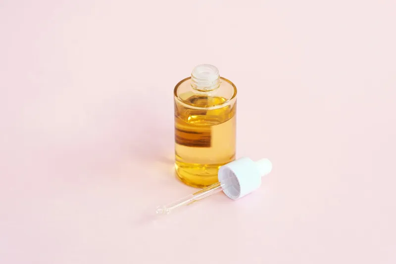 Skincare serum bottle and dropper on a pink background
