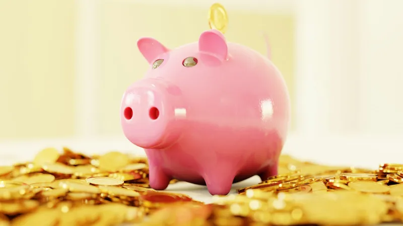 Pink piggy bank surrounded by gold coins