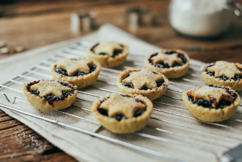 Homemade mince pies with star-shaped tops cooling on a wire rack