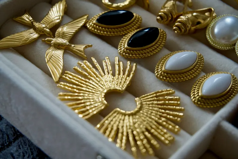 Vintage gold earrings and brooches with black, white and pearl stones in a jewellery box