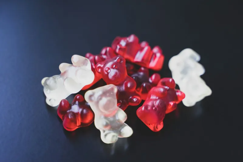 Red and clear gummy sweets on a dark surface