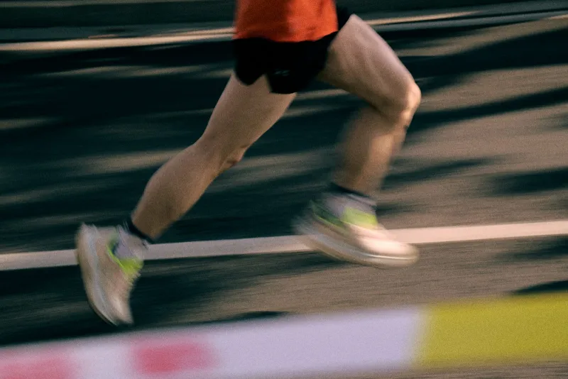 A runner's legs in motion on an athletics track, blurred with speed