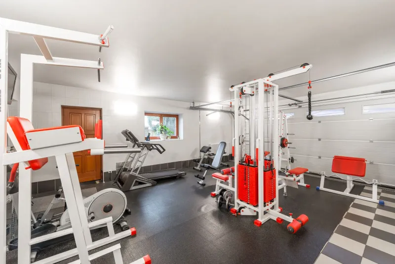 A home gym with a treadmill, cross trainer and weight machines on a dark rubber floor