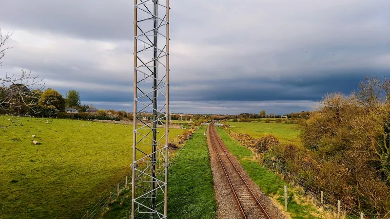 A railway line running through green countryside under a cloudy sky