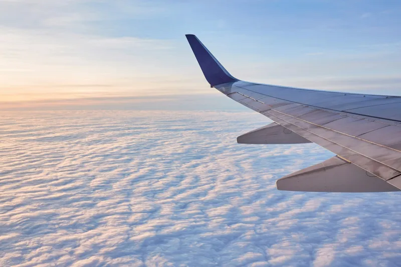 Aircraft wing above a sea of clouds at sunrise