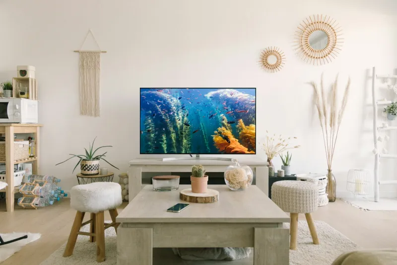 A flat-screen TV on a stand in a bright living room