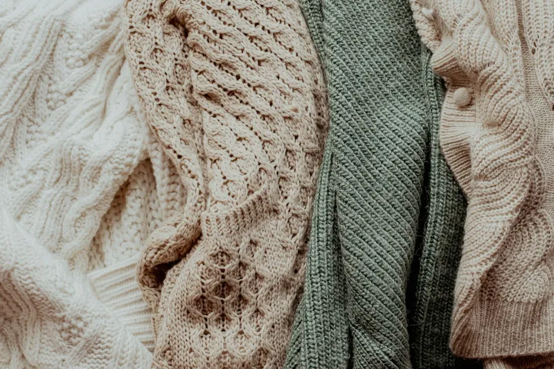 A pile of knitted jumpers stacked together