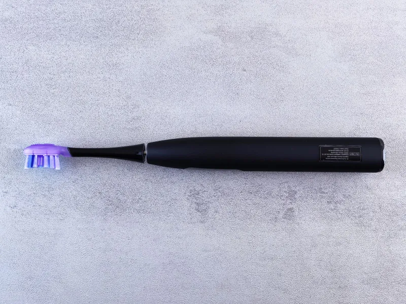 Black electric toothbrush lying on a grey stone surface