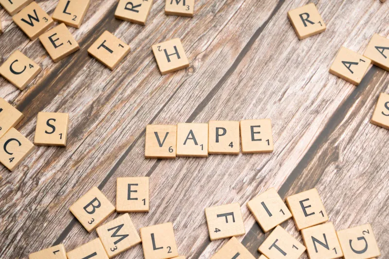 Wooden letter tiles spelling the word vape on a weathered wooden table