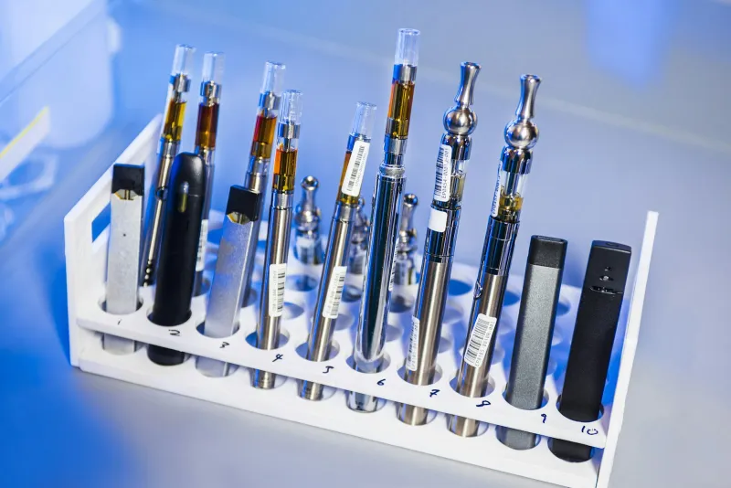 Vawoo: a vaping marketplace for kits, mods and coils A row of assorted vape pens and pod devices in a white rack