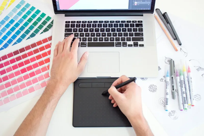 VectorStock: royalty-free vector art by the image, credit or subscription Hands using a laptop and drawing tablet beside colour swatches and marker pens