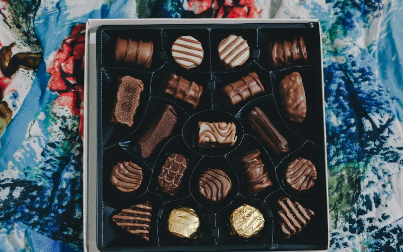 A box of assorted chocolates on a colourful patterned cloth
