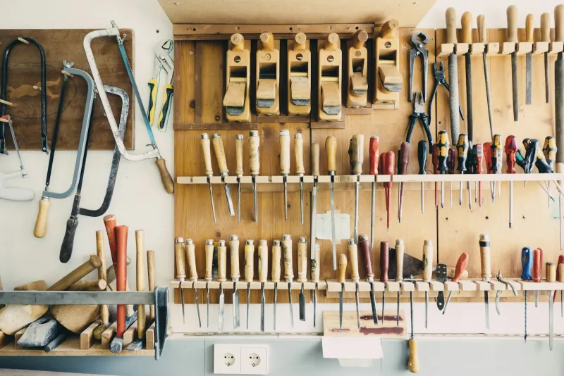Hand tools, saws and chisels neatly arranged on a wooden workshop wall rack