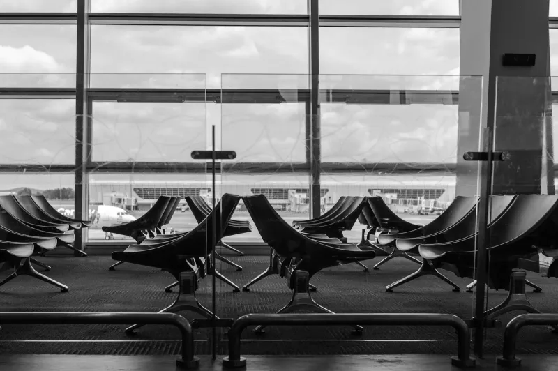 Empty airport departure seating in front of large windows overlooking the apron