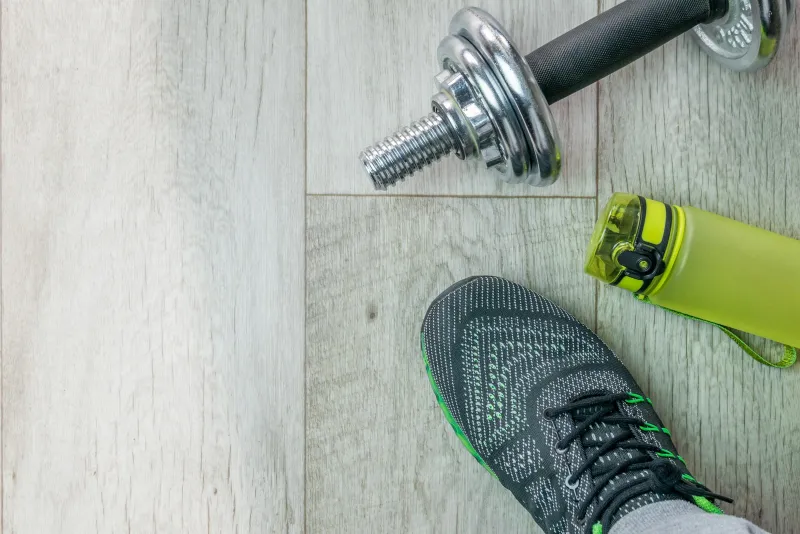 Vitamin Essence store spotlight: Hydrotine drink-mix sticks from VE A trainer, a dumbbell and a green water bottle on a light wooden floor