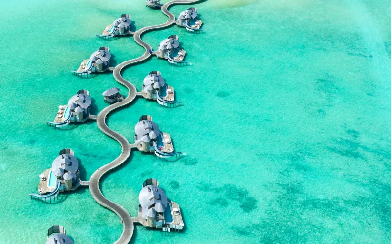 Aerial view of overwater bungalows linked by wooden walkways in a turquoise lagoon