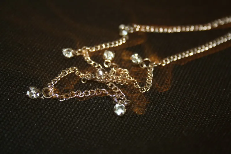 Fine chain necklace with clear stones on dark fabric