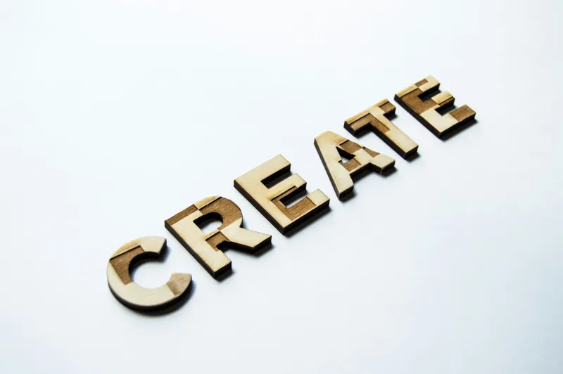 Laser-cut wooden letters spelling CREATE on a white surface