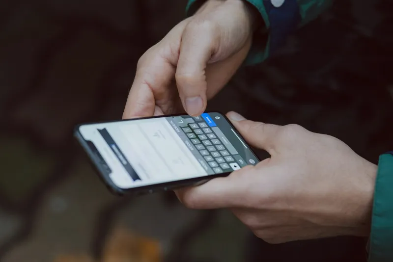 Hands typing on a smartphone keyboard