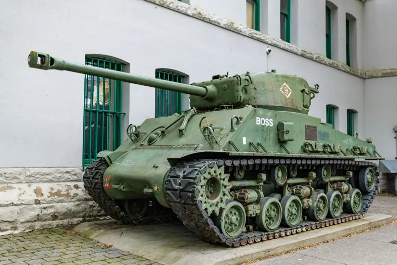 A green Sherman tank on display outside a white stone building