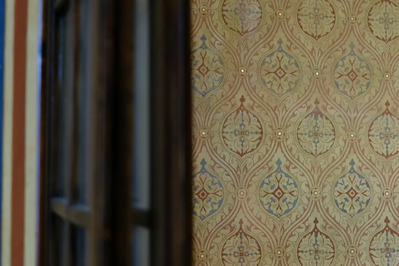 Ornate vintage patterned wallpaper beside a dark wooden window frame