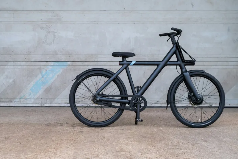 Black electric bike standing in front of a grey concrete wall