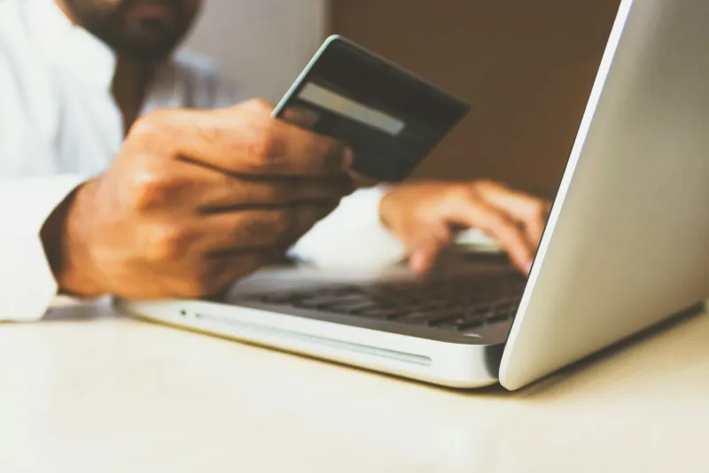 Person holding a bank card while shopping on a laptop